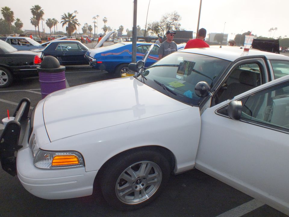 White Ford Crown Victoria sedan front three-quarter view at an outdoor car show parking lot