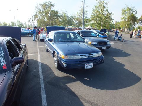 2003 Ford Crown Victoria - blue Ford sedan shown front three-quarter at a car show, displaying a vanity license plate reading NARCPTR.