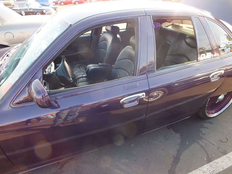Side of a dark purple sedan showing black leather interior through open windows