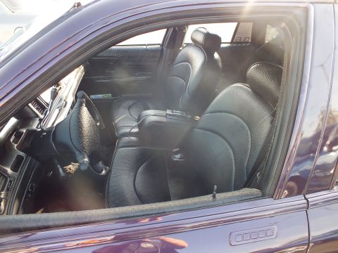 2003 Ford Crown Victoria - View through a purple sedan's window of custom black leather front bucket seats with a center console.