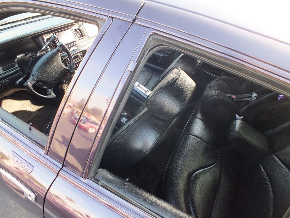Black leather custom interior of a purple sedan viewed through open rear window
