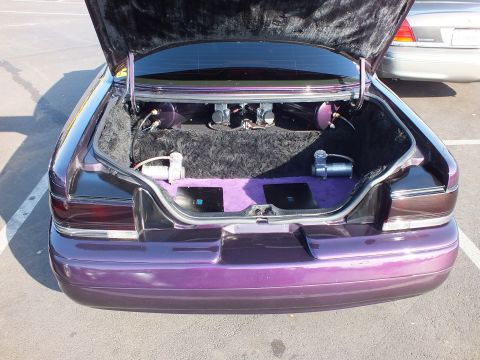 2003 Ford Crown Victoria - Close view into a purple sedan's open trunk showing hydraulic pumps, plumbing and purple carpeting of a custom setup.