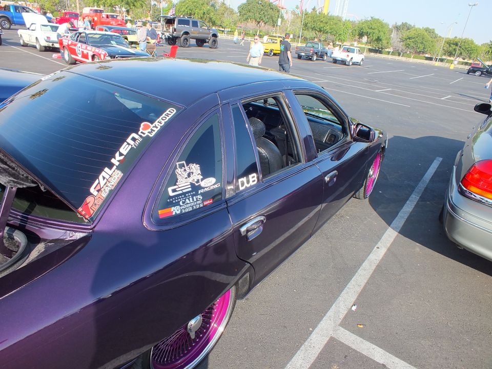 Rear quarter window of a purple sedan covered in stickers including Falken and DUB decals
