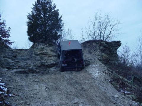 1992 Ford Bronco - A Jeep Wrangler navigates a challenging off-road trail with steep, rocky terrain.