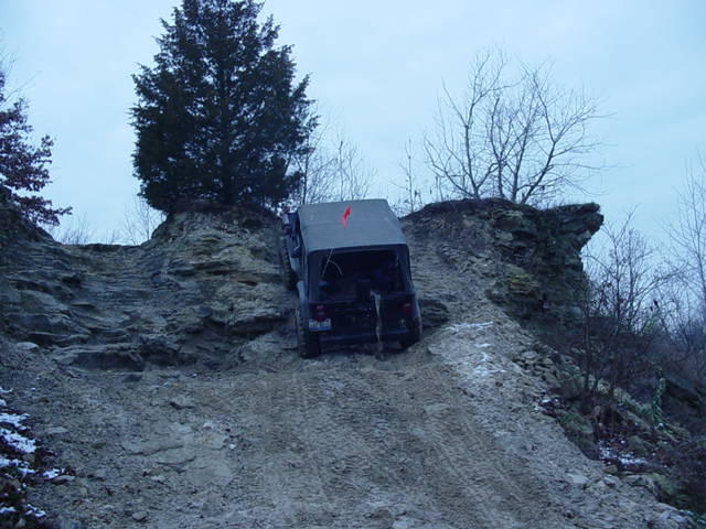 Dark gray Jeep Wrangler climbing a steep, rocky incline