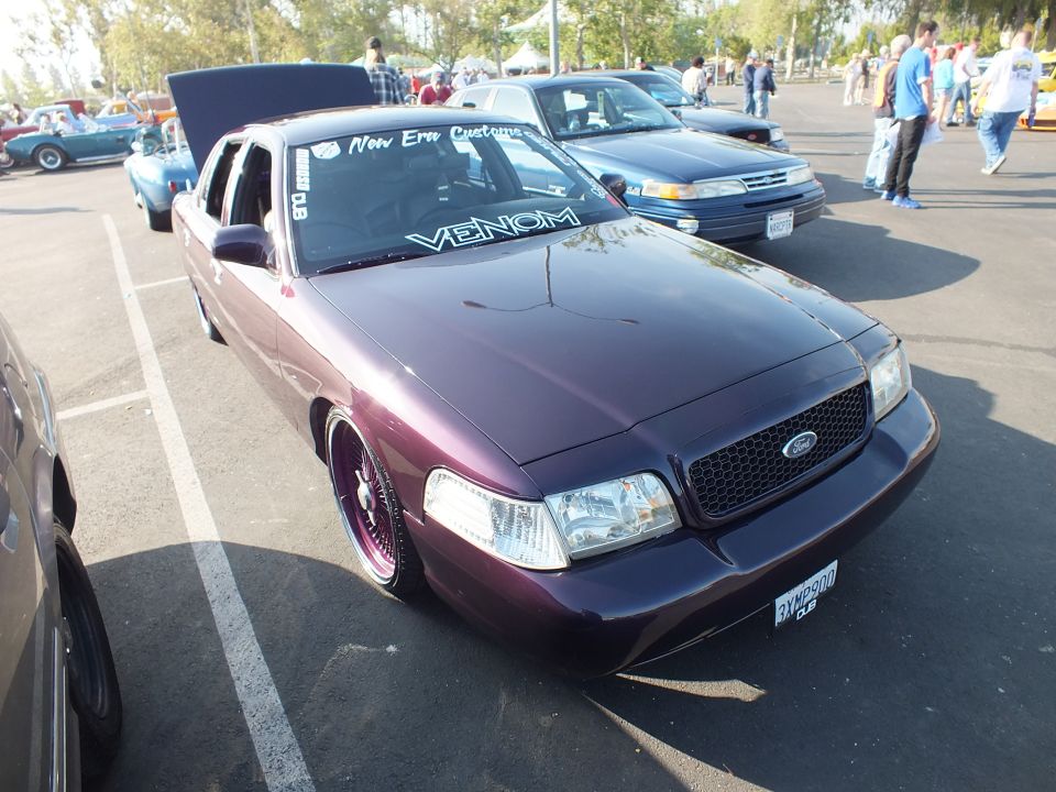 Front three-quarter of a low purple Ford sedan with a blacked-out grille and Ford emblem