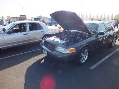 2003 Ford Crown Victoria - dark gray Ford Crown Victoria sits with its hood raised to display the engine bay, parked among silver sedans at a meet.
