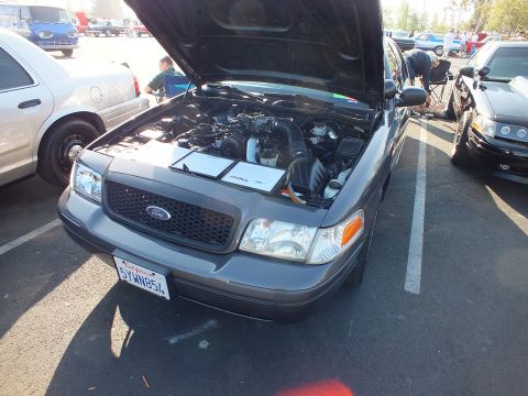 2003 Ford Crown Victoria - dark gray Ford Crown Victoria sits with hood raised, its black grille bearing the Ford oval above a California plate.