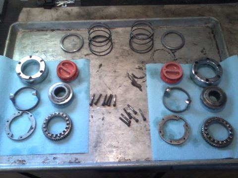1970 Ford Bronco - Various disassembled vehicle drivetrain components are organized on a workbench for inspection or repair.