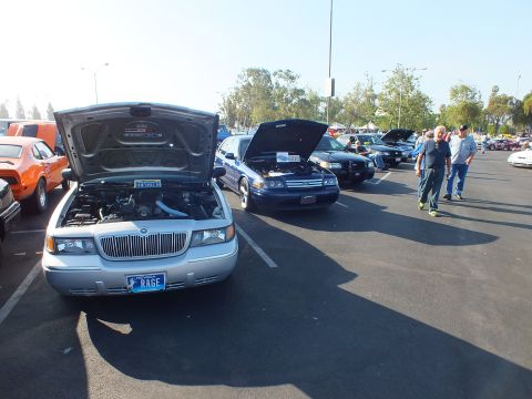 2003 Ford Crown Victoria - silver Mercury Grand Marquis sits head-on with its hood raised and a RAGE plate amid a row of show sedans.
