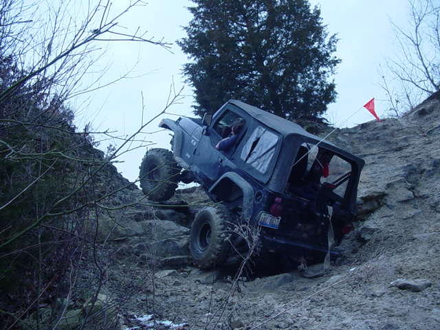 Jeep Wrangler climbing a steep, rocky hill with a red flag on top