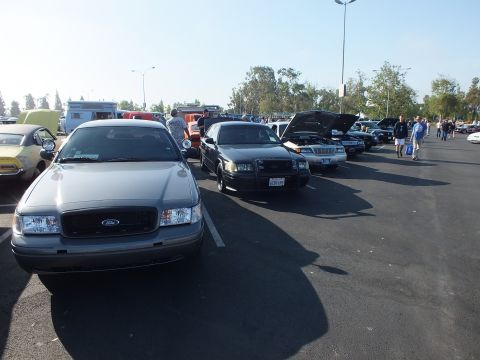 2003 Ford Crown Victoria - silver Ford Crown Victoria leads a row of dark Panther-platform sedans at a sunny parking-lot car show.