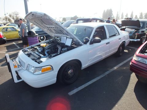 2003 Ford Crown Victoria - white Ford Crown Victoria with front push bar displays its engine bay with the hood raised at a car show.