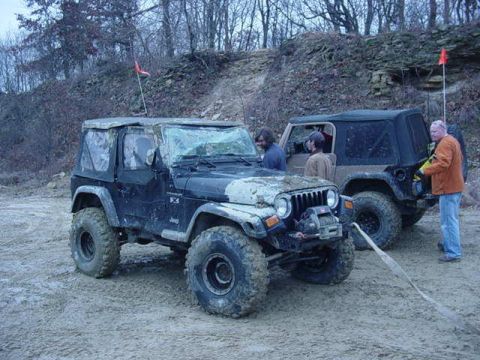 1992 Ford Bronco - Two Jeep Wranglers are parked on a dirt surface, with people standing near them.