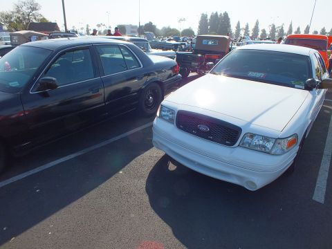 2003 Ford Crown Victoria - white Ford Crown Victoria with a body-color front bumper parked next to a black sedan in a sunny parking lot car show.