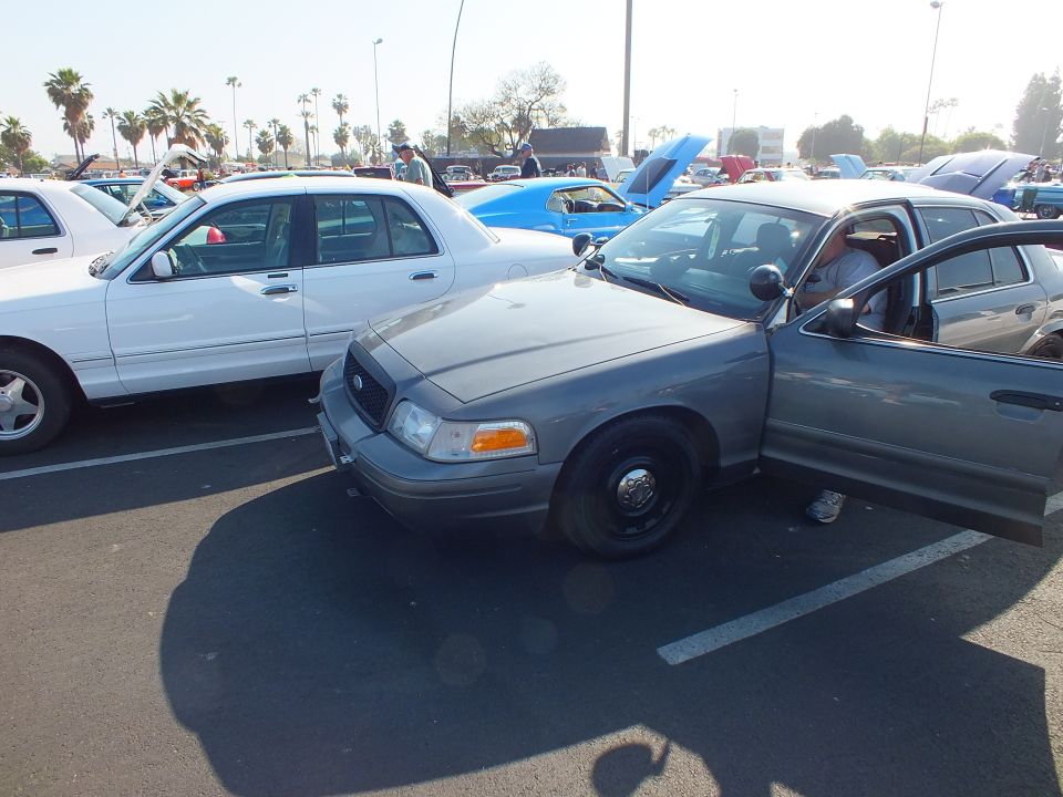 Gray Ford Crown Victoria with black steel wheels at an outdoor car show