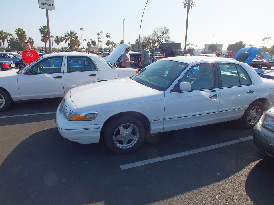 White sedan with five-spoke wheels parked at an outdoor car show