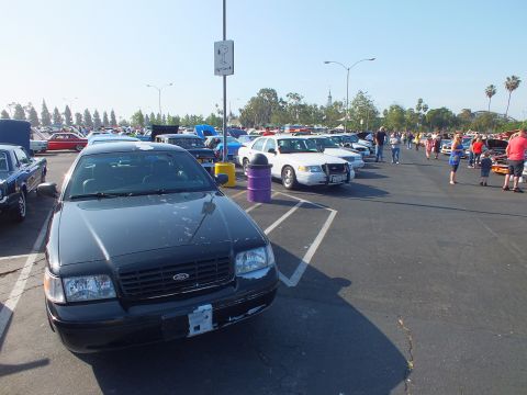 2003 Ford Crown Victoria - black Ford Crown Victoria parked front-on with people and rows of cars filling the sunny show lot behind it.