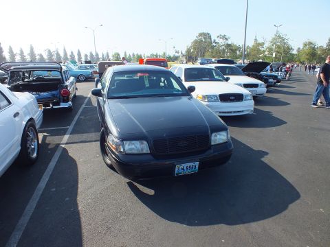 2003 Ford Crown Victoria - black Ford Crown Victoria with California plate 3X9866 parked nose-out among other sedans at a sunny outdoor car show.