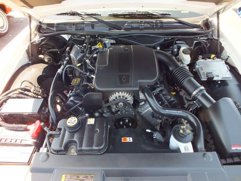 2003 Ford Crown Victoria - detailed view of a clean V8 engine bay with air intake and battery, hood raised at a car show.
