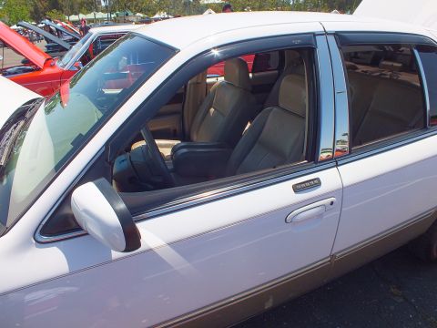 2003 Ford Crown Victoria - Looking through the open windows of a white sedan reveals tan leather front seats and chrome trim with vent visors.