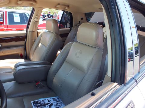 2003 Ford Crown Victoria - tan leather front seats of a Mercury sedan, embossed Mercury emblems on the seatbacks, with a flyer on the seat.
