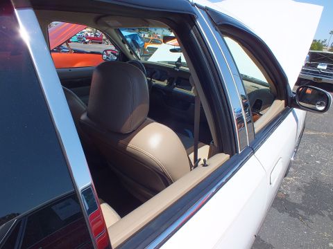 2003 Ford Crown Victoria - Looking through the open rear window of a sedan at its tan leather rear seats and chrome window trim.