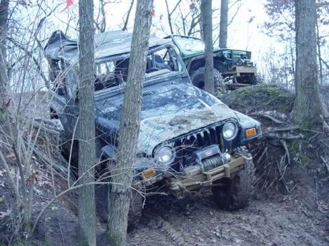 1992 Ford Bronco - Two Jeep Wranglers navigating a muddy, wooded off-road course.