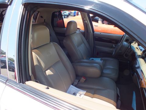 2003 Ford Crown Victoria - Interior of a full-size sedan with tan leather front seats, dark dashboard, and a printed display card on the seat.