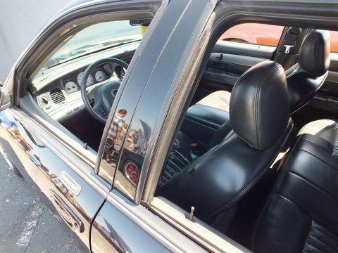2003 Ford Crown Victoria - Looking through the side window of a black sedan at its black leather front seats and instrument panel.