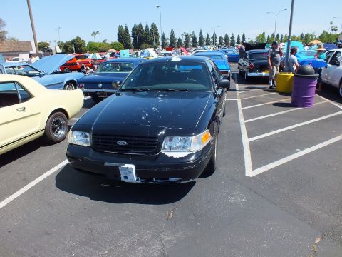 2003 Ford Crown Victoria - Front view of a black Ford full-size sedan fitted with a police-style push bar, parked at a sunny car show.