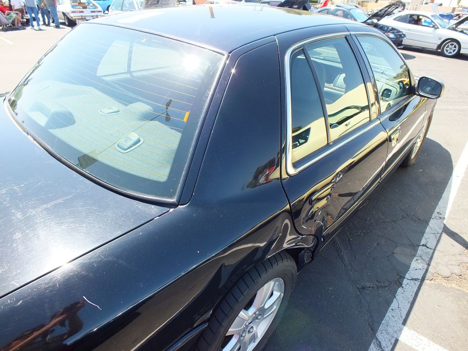 Black sedan rear three-quarter view with tan interior visible