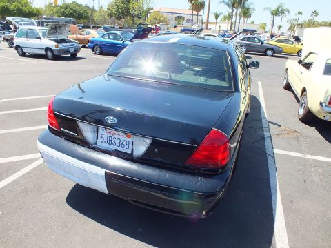 2003 Ford Crown Victoria - Rear of a black Ford four-door sedan with red taillights and California plate 5JBS368, parked at a car show.