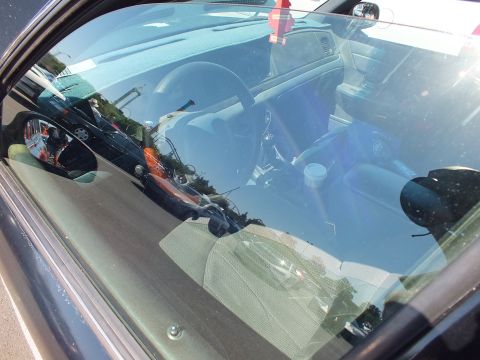 2003 Ford Crown Victoria - view through the windshield of a sedan showing the steering wheel, dashboard and interior with heavy sky reflections.