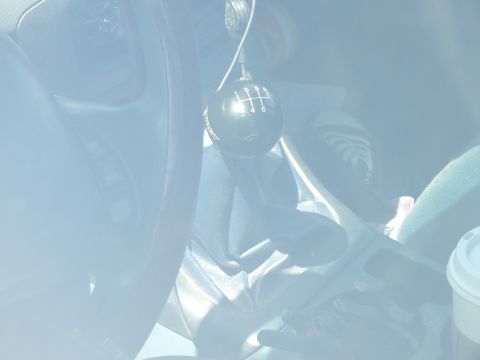 2003 Ford Crown Victoria - close-up of a manual transmission shifter with a six-speed pattern knob beside a leather-wrapped steering wheel.