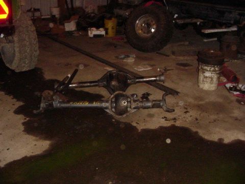 1992 Ford Bronco - Two differential axles are on the floor of a garage, one with visible yellow text.