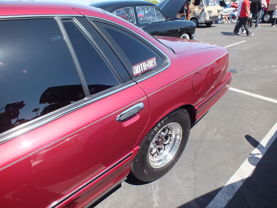 Rear quarter of a dark red sedan with chrome slotted wheel and ADTR.net window decal
