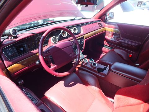 Custom car interior with red leather, wood dash trim and burgundy leather-wrapped wheel