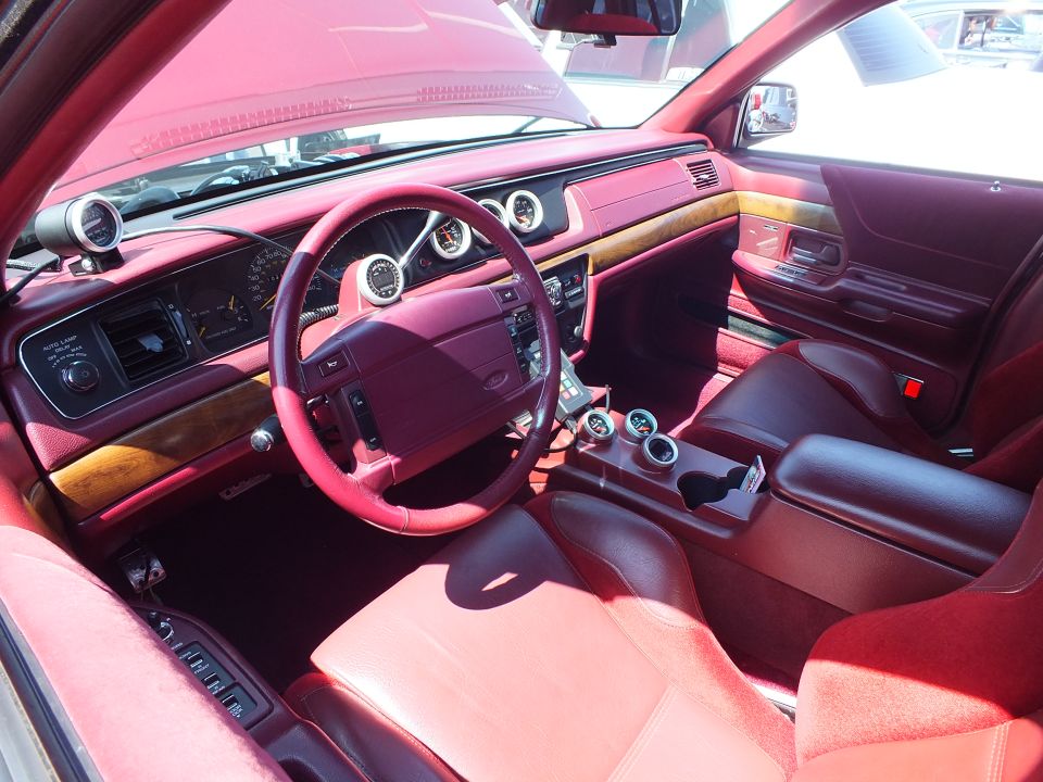 Custom car interior with red leather, wood dash trim and burgundy leather-wrapped wheel