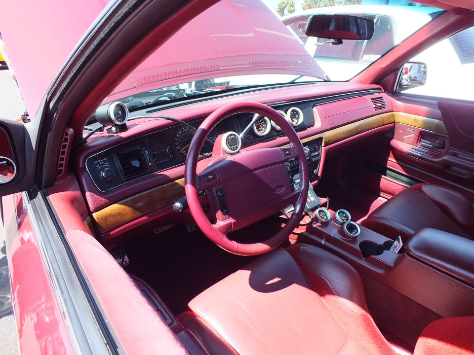 Custom dashboard with burgundy leather wheel, wood trim and red seats viewed from the door