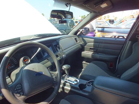 Interior of a Ford sedan viewed from passenger side with Ford wheel, gauge and gray seats