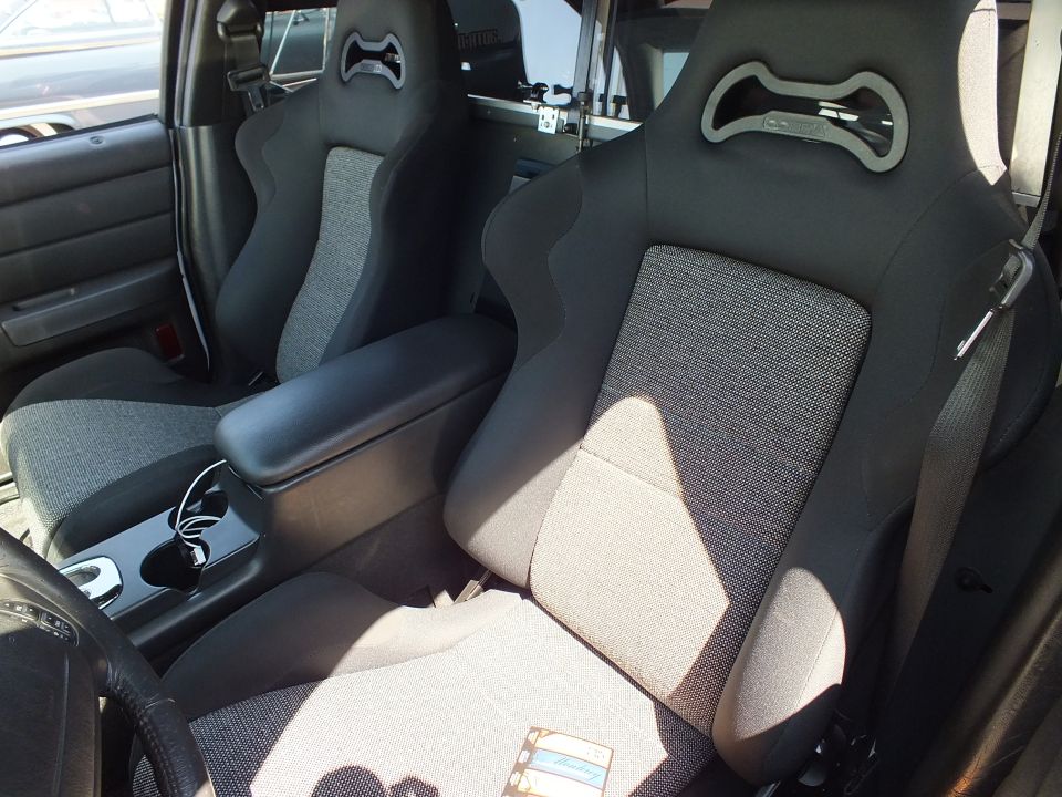 Black and gray aftermarket sport bucket seats with cutout headrests in a vehicle front row