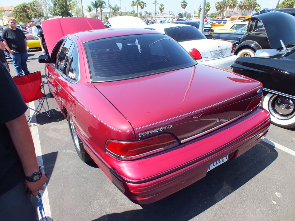Rear three-quarter view of a red Ford Crown Victoria sedan at a car show