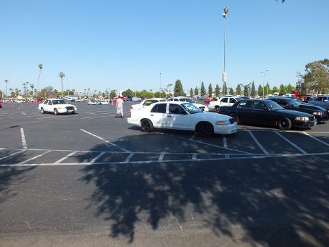 White full-size sedan with black wheels beside a dark cruiser in a parking lot