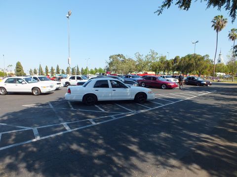 White full-size sedan on black wheels parked in a wide sunny lot