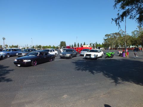 Black sedan, white cruiser and a green motorcycle in a sunny lot