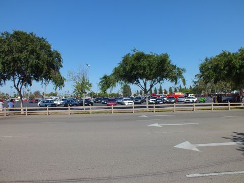 Cars parked across a lot beyond a post-and-rail fence under a clear blue sky