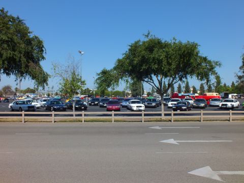 Mixed parked cars including a maroon sedan behind a wooden fence