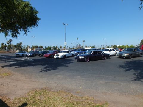 Lowered black sedan with purple wheels among parked cars in a lot