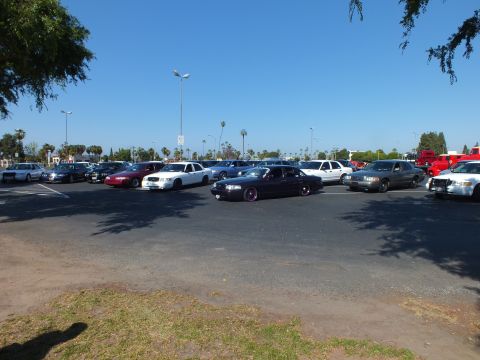 Lowered black sedan with purple wheels parked in an open lot